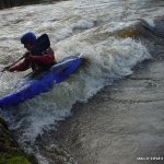 Photo of the Owennashad river in County Waterford Ireland. Pictures of Irish whitewater kayaking and canoeing. Matt side surfs the foam pile by the wall on blackwater play wave. Photo by Michael Flynn
