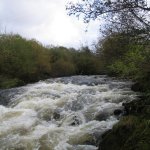 Photo of the Nire river in County Waterford Ireland. Pictures of Irish whitewater kayaking and canoeing. The big rapid on the river running into a small gorge section a house is perched high on the left bank at the bottom of the rapid before the bends through the little gorge. Photo by Michael Flynn
